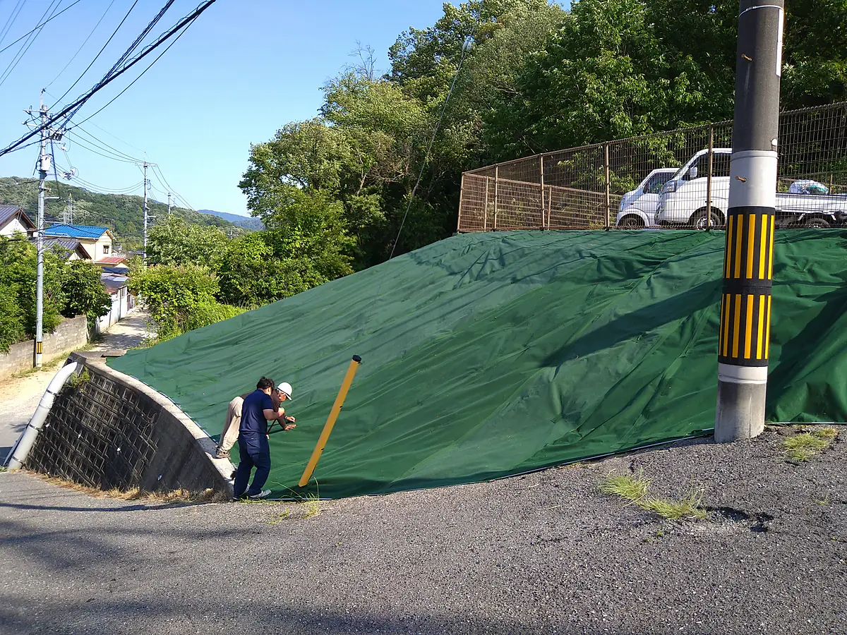 施工後：同じ法面に緑色の防草シートを張り終えた状態
